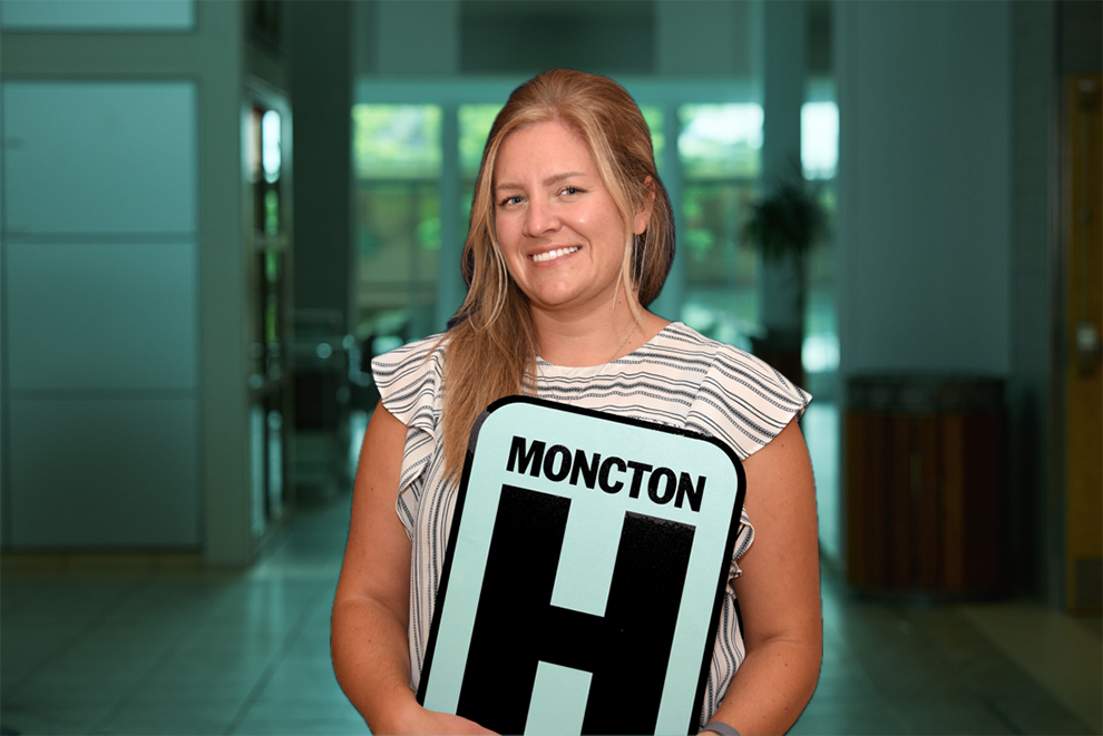 Annick Ouellette tient une pancarte H et sourit à la caméra