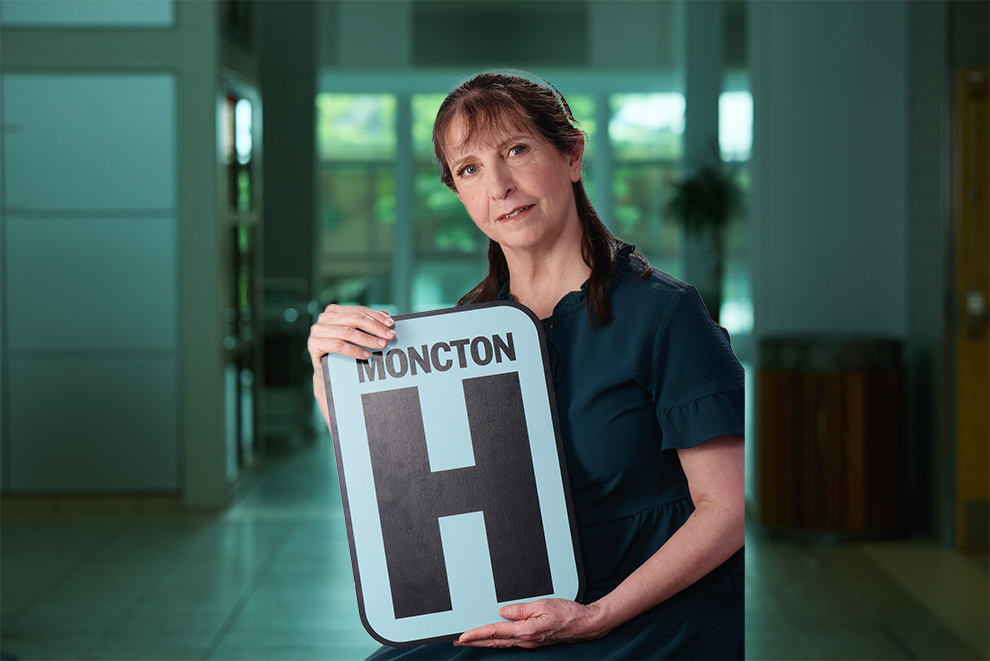 Ashraf Rahmani tient un panneau H et sourit à la caméra