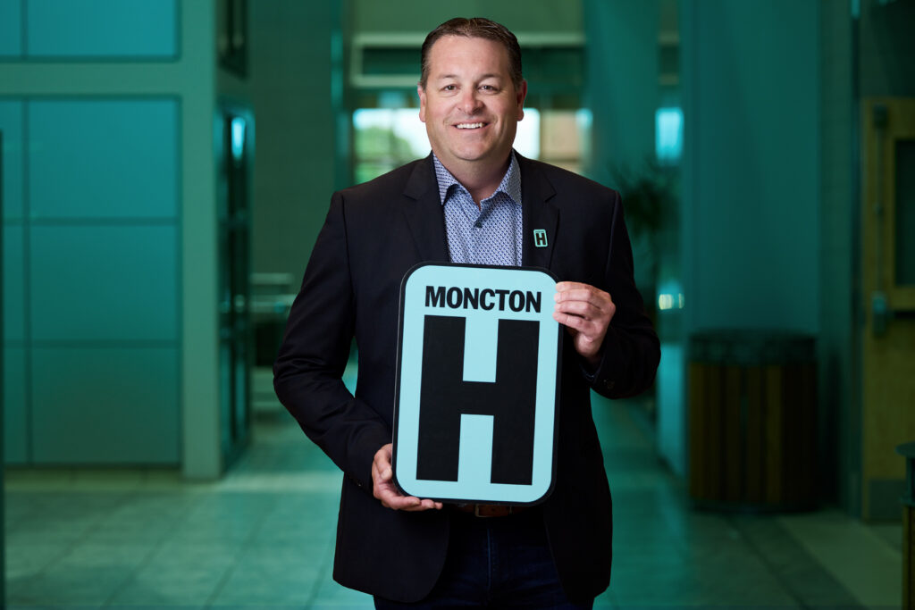 Dallas McCready Holding H Sign and Smiling at camera