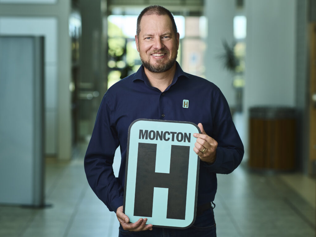 Dr. Ken Gillespe Holding H Sign and Smiling at camera
