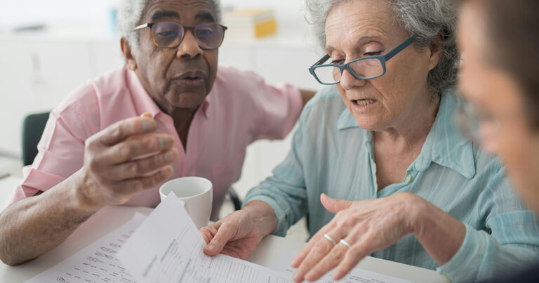 Couple de personnes âgées regardant des documents