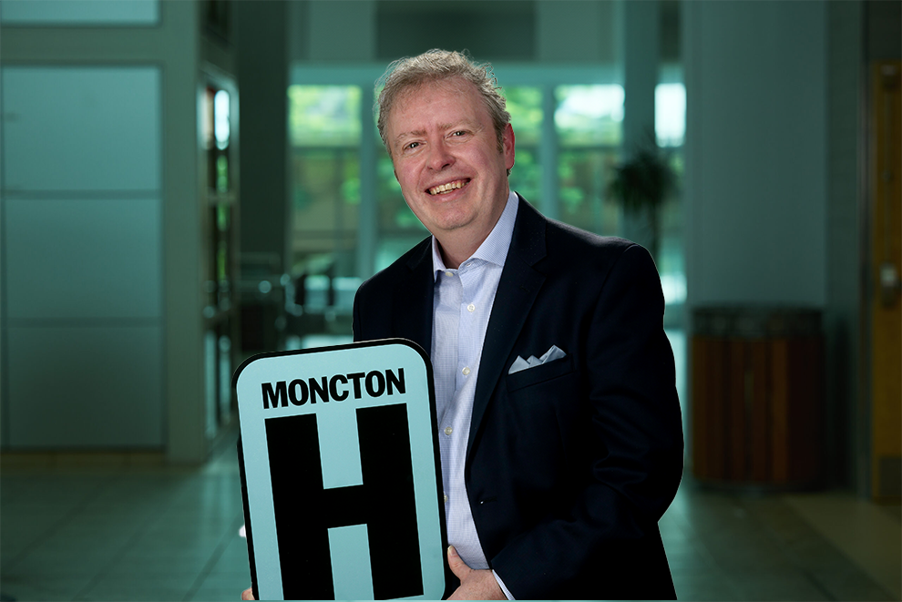 Jason Tremere tient le panneau H et sourit à la caméra