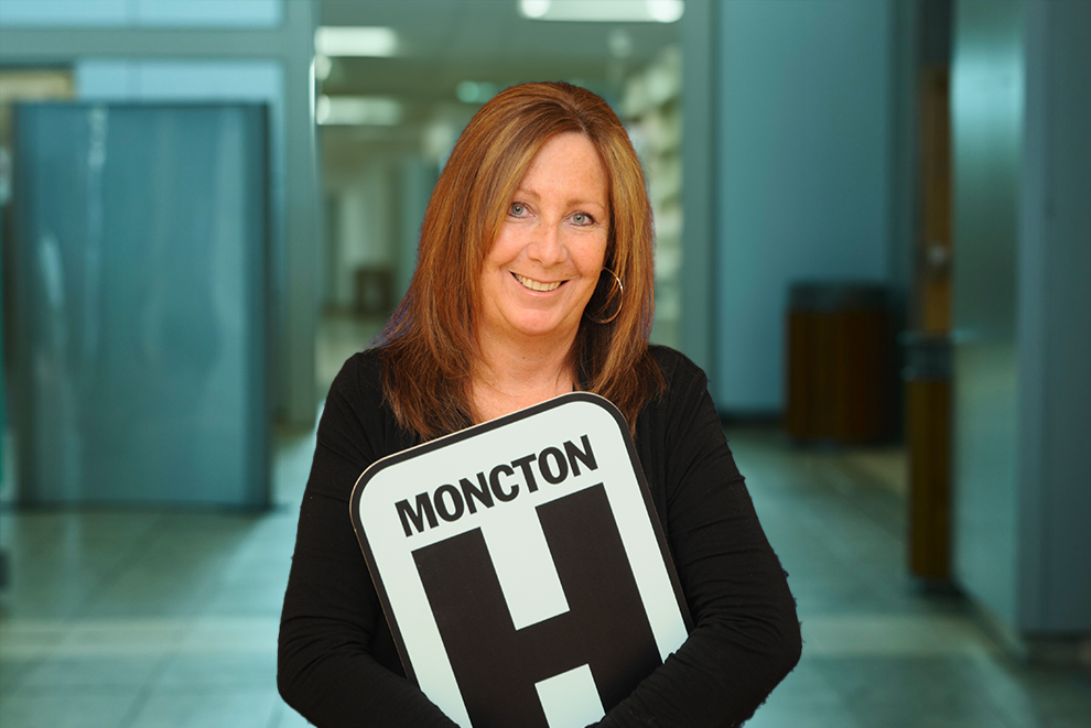 Julie Thebeau tient une pancarte H et sourit à la caméra