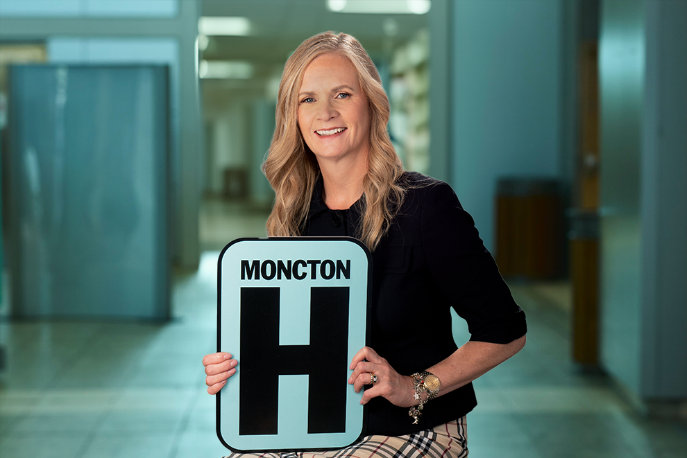 Katherine Robertson tient une pancarte H et sourit à la caméra