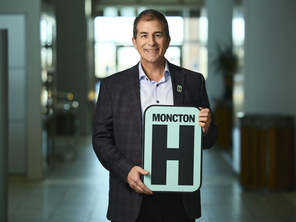 Mike Robart Holding H Sign and Smiling at camera