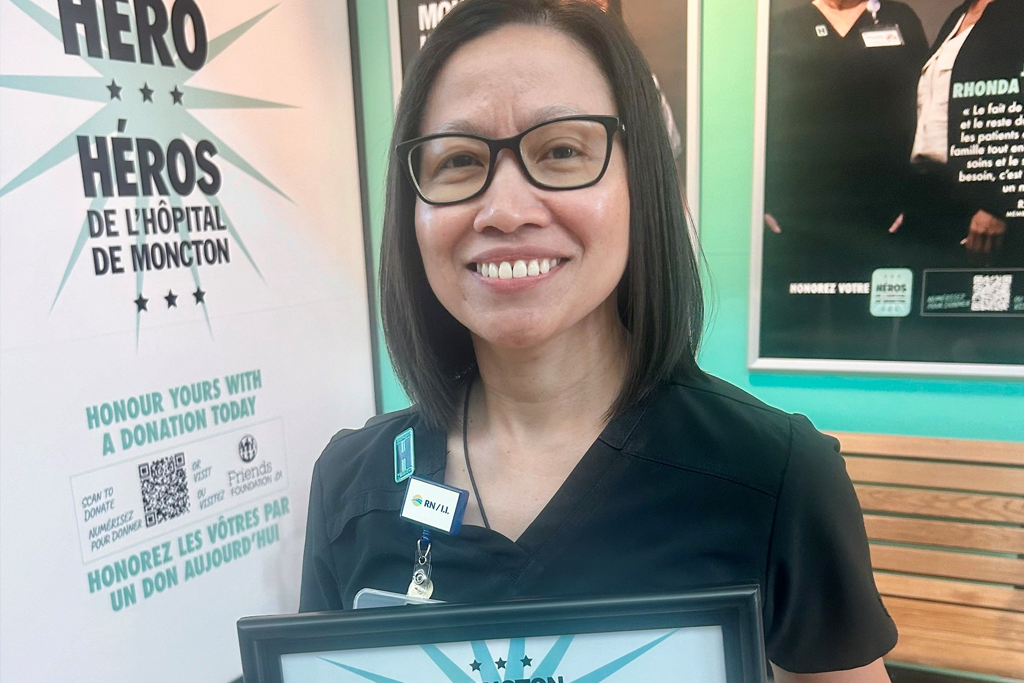 Rose Ehimplar Gizza, RN, tenant une plaque de héros de l'hôpital