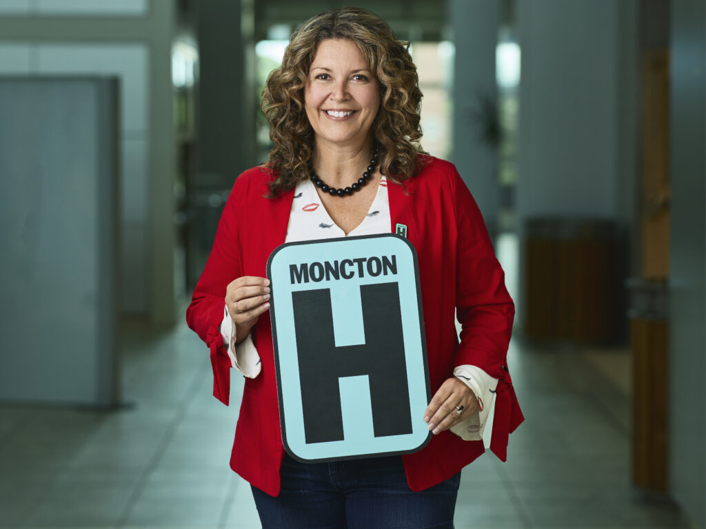 Tracy Clinch tenant un signe H et souriant à la caméra