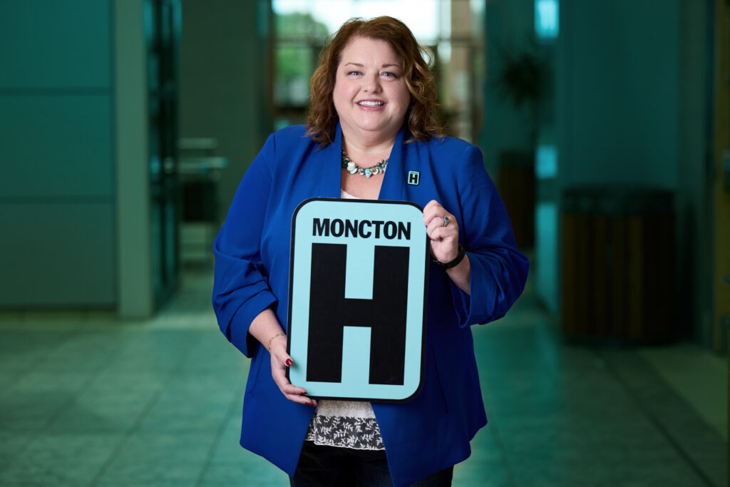 Tina Smith Holding H Sign and Smiling at camera