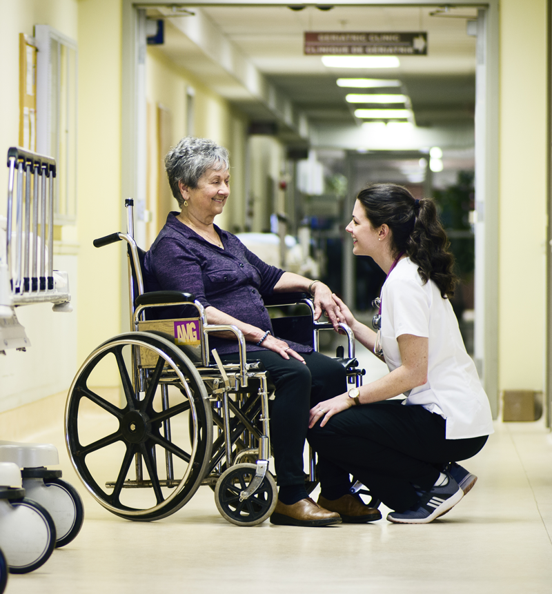 Dame en fauteuil roulant avec une soignante, souriant