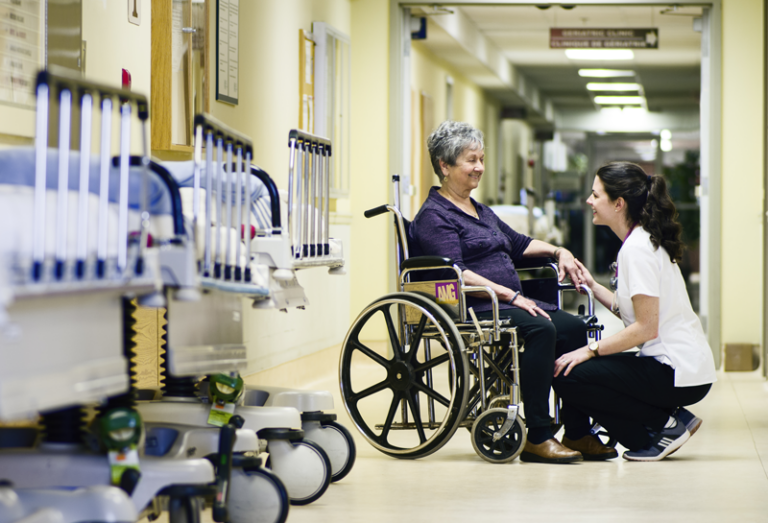 Dame en fauteuil roulant avec une soignante, souriant
