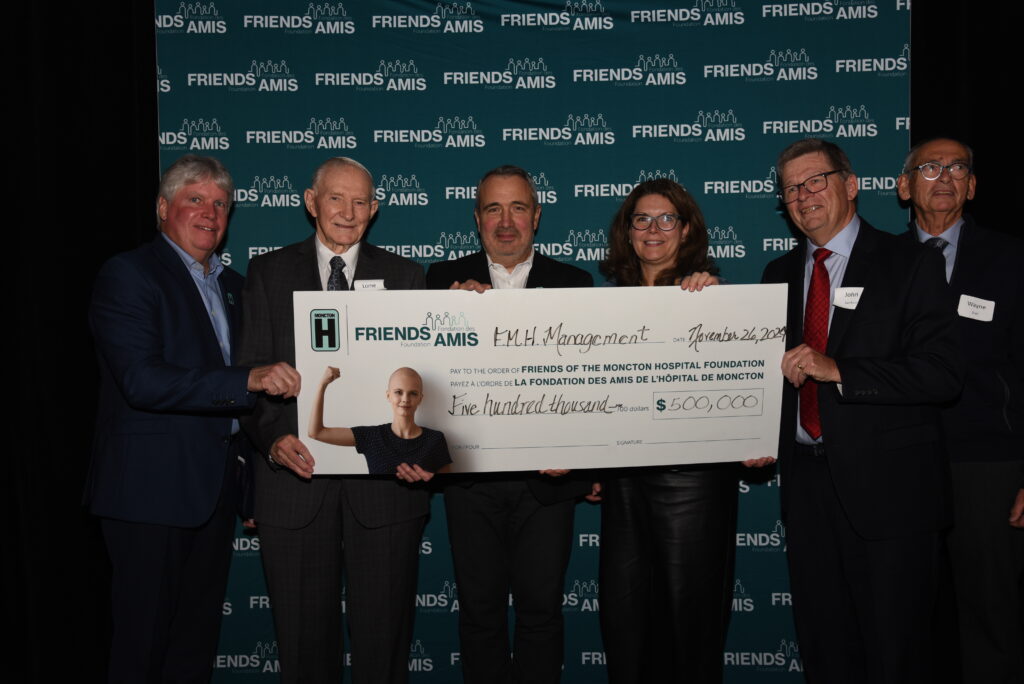 Groupe de personnes tenant un gros chèque lors de la présentation du chèque